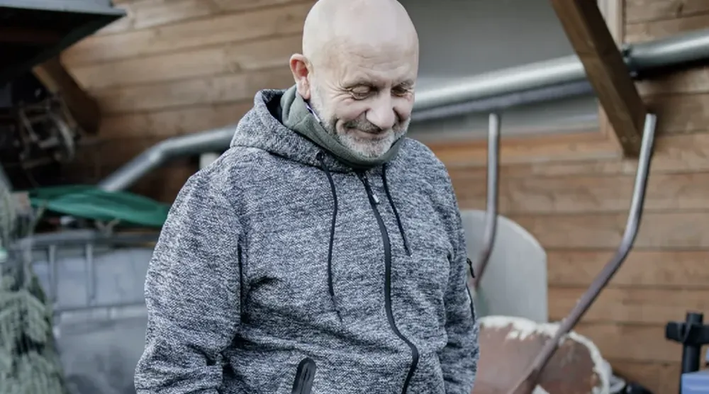 Muž v pletené mikině na dvorku